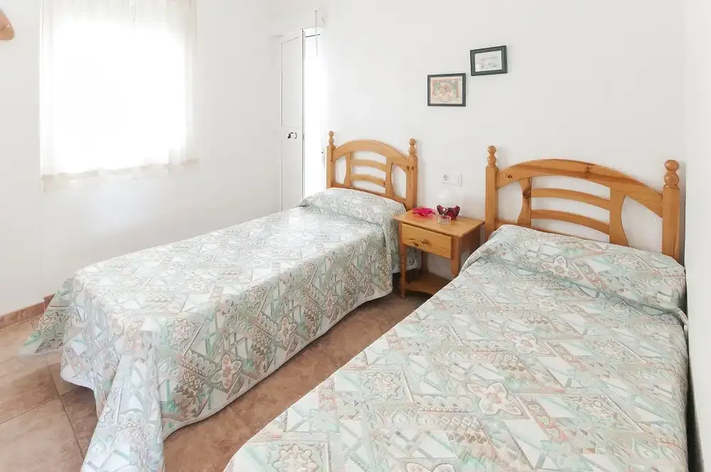 Dormitorio con dos camas y una pequeña mesita de noche.