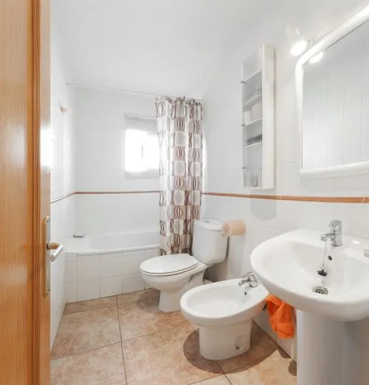 Un baño con bañera, cortina de ducha, lavabo y bidé.