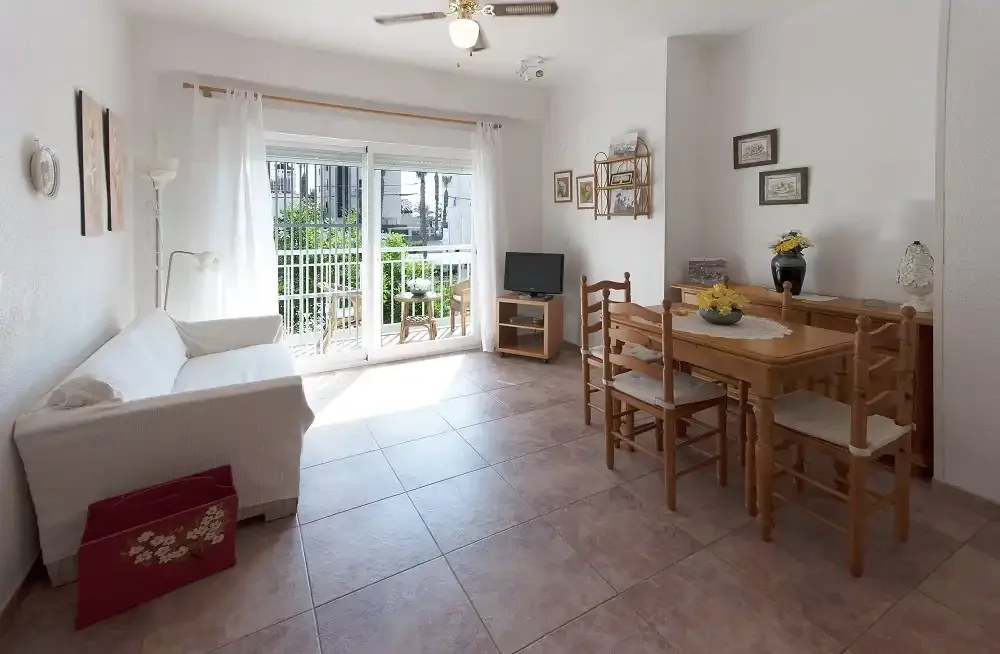 Una luminosa sala de estar y comedor se abre a un balcón mediante puertas correderas de cristal.