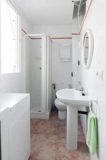A bright bathroom with a pedestal sink and a glass shower.