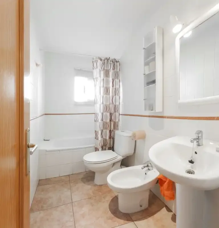 Un baño luminoso con bañera, inodoro, bidé y lavabo.