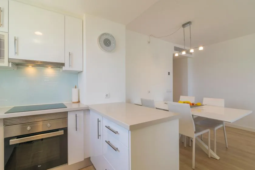 A bright kitchen and dining area with white cabinetry and a long table.