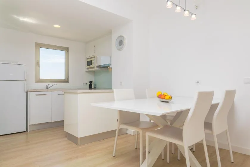 A bright kitchen and dining area with a white table and seating.