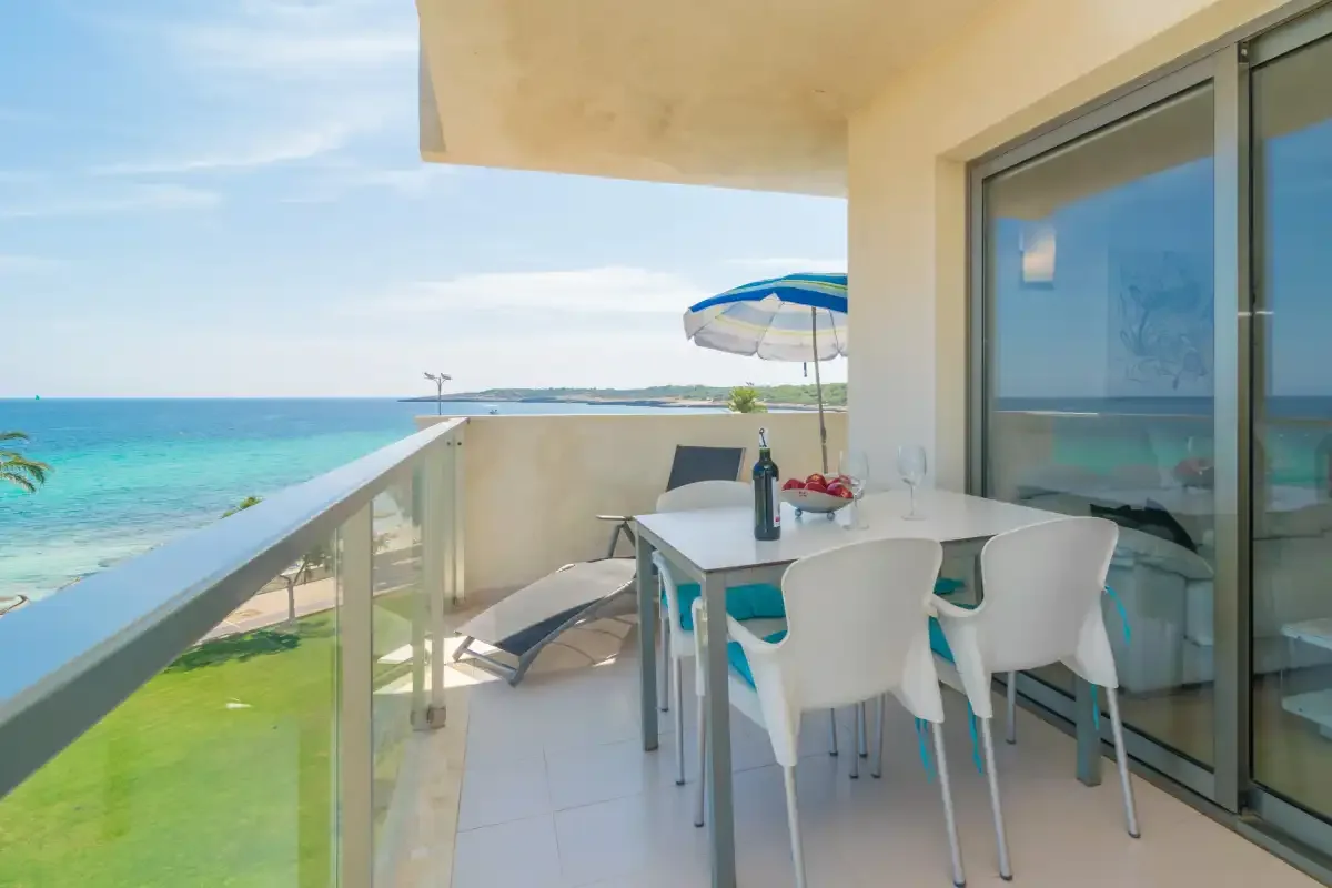 A seaside balcony with a dining table, chairs, and views of the water.