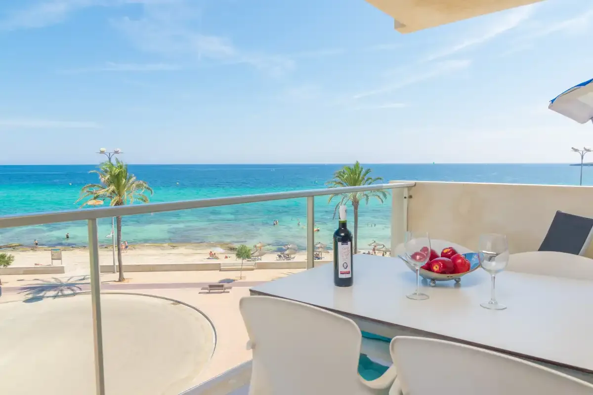 A seaside balcony dining area overlooks the beach and turquoise water.