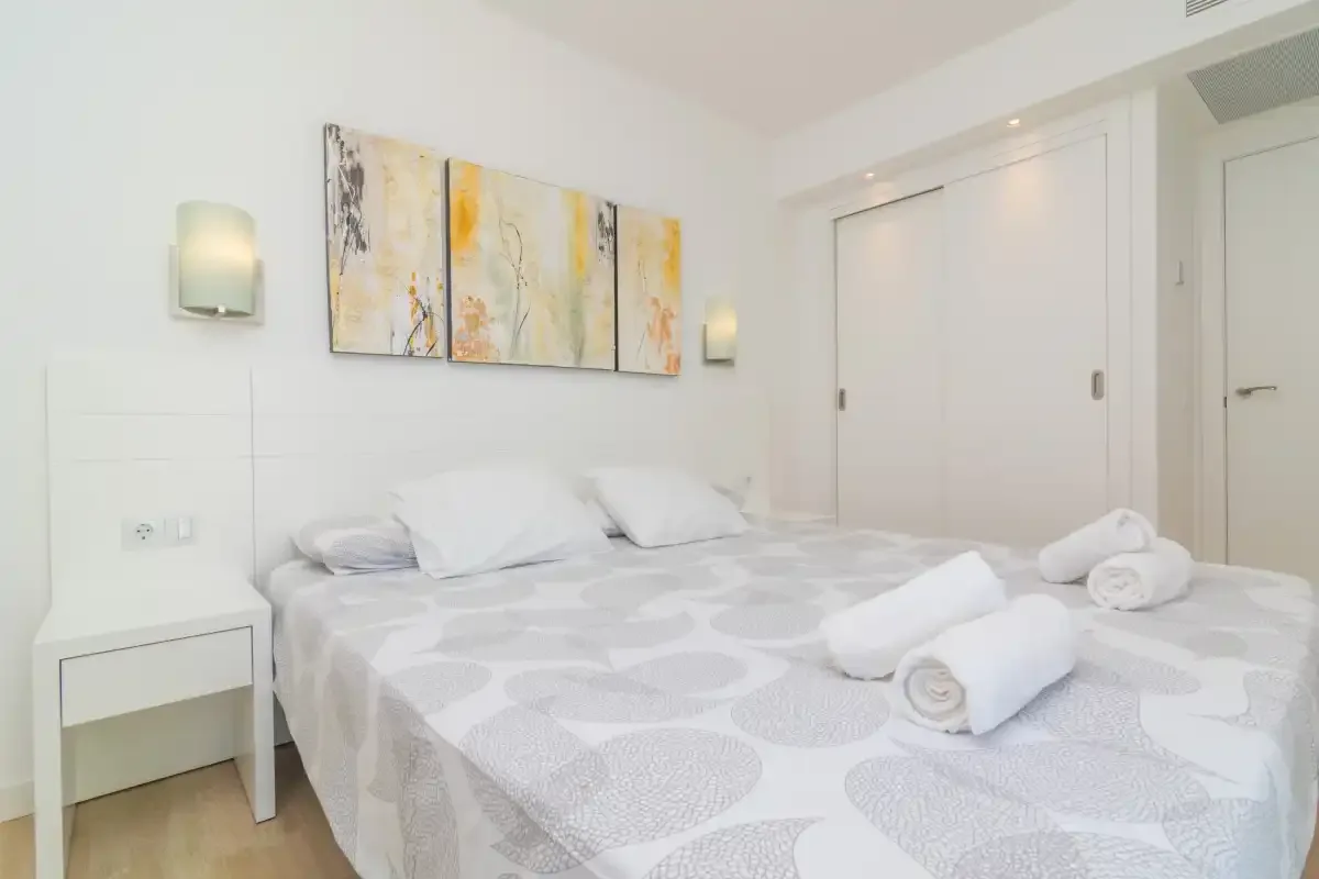 A bright bedroom with a large bed and abstract wall art.