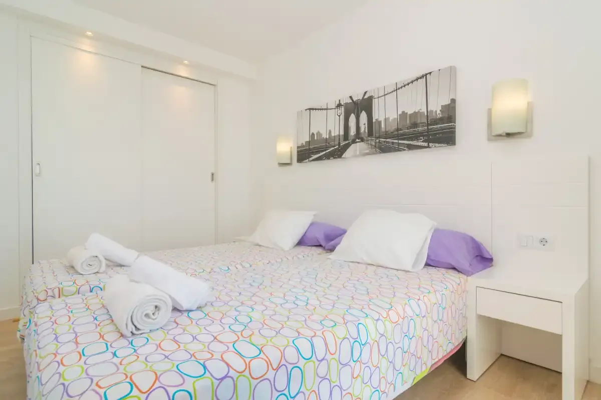 A bedroom with a bed covered in colorful patterned bedding and white pillows.