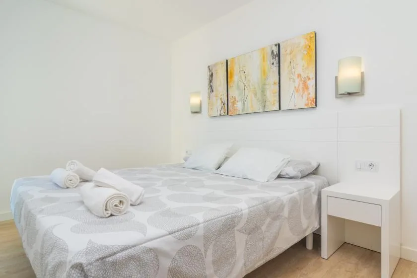 A bedroom with a bed, pale patterned bedding, and abstract wall art.