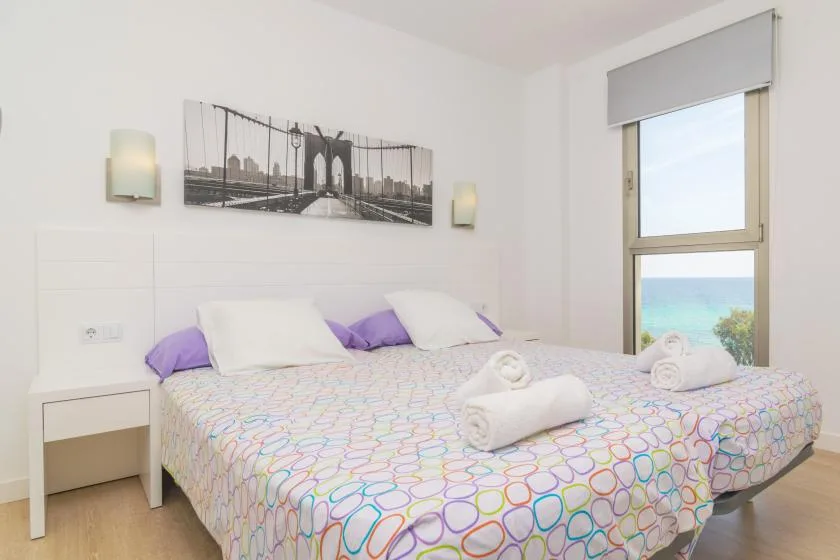 A bedroom with a patterned bedspread and a window overlooking the sea.