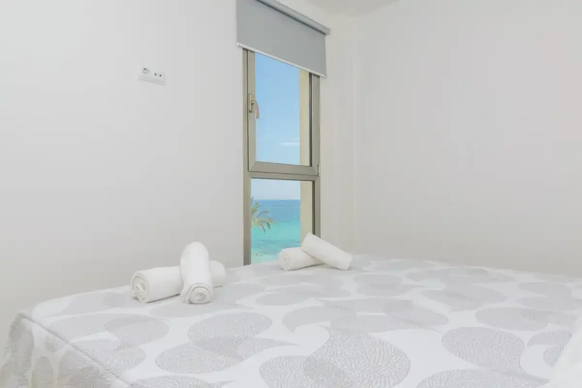 A bedroom with a bed and a window overlooking the sea.
