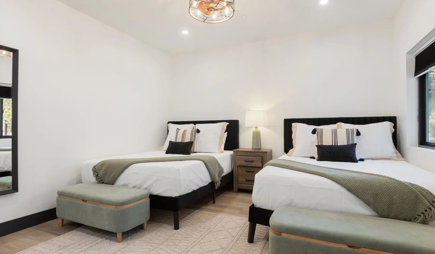 Un dormitorio luminoso con dos camas, ropa de cama neutra y una mesita de noche.