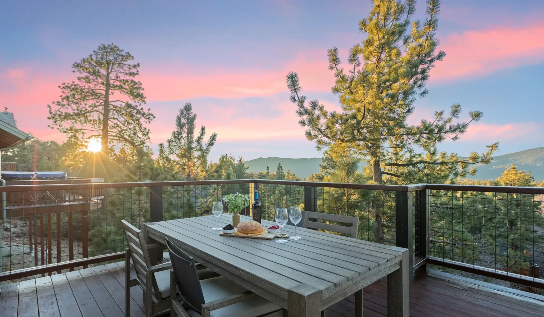 Un comedor al aire libre con mesa y sillas ofrece vistas de árboles al atardecer.