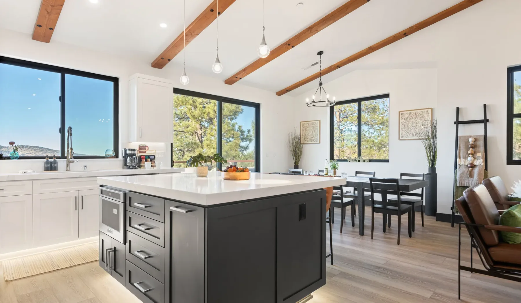 Una luminosa cocina y comedor con una gran isla y vigas expuestas en el techo.