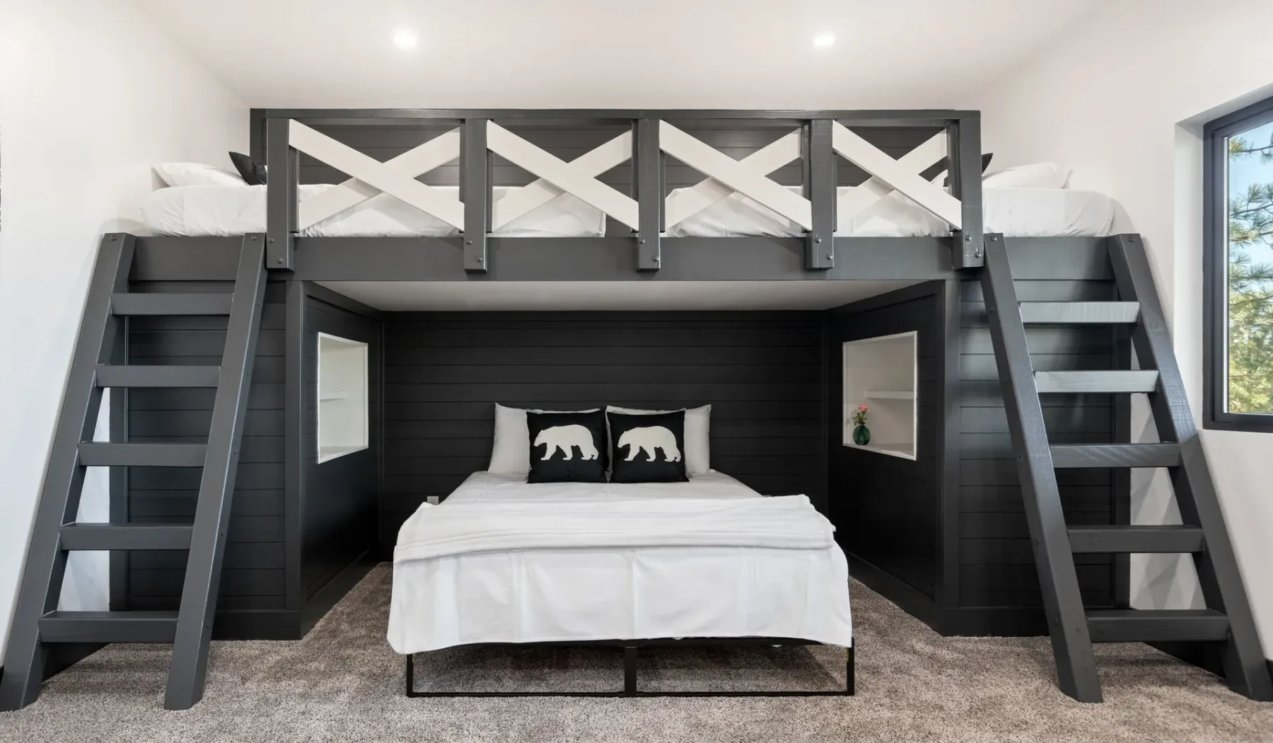 Un dormitorio tiene una cama bajo una plataforma elevada para dormir, con escaleras a ambos lados.