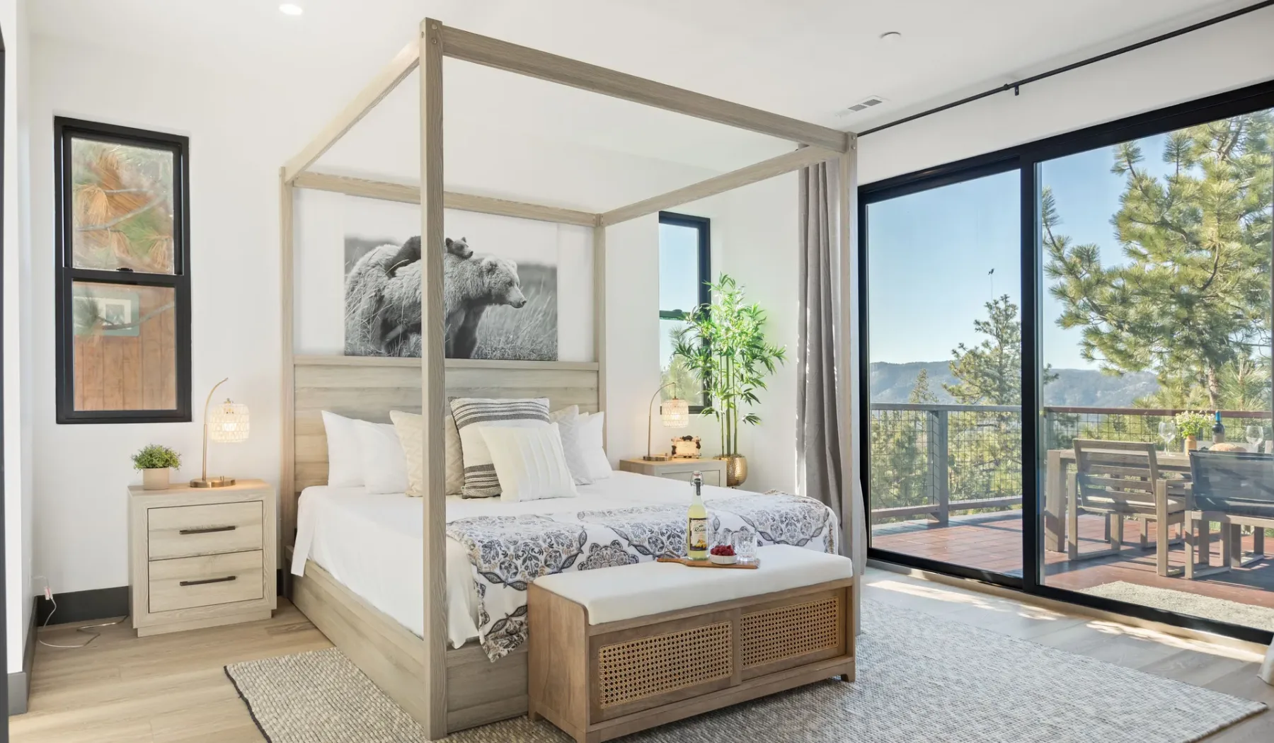 Un dormitorio luminoso cuenta con una cama con dosel junto a grandes ventanales que dan a un balcón.
