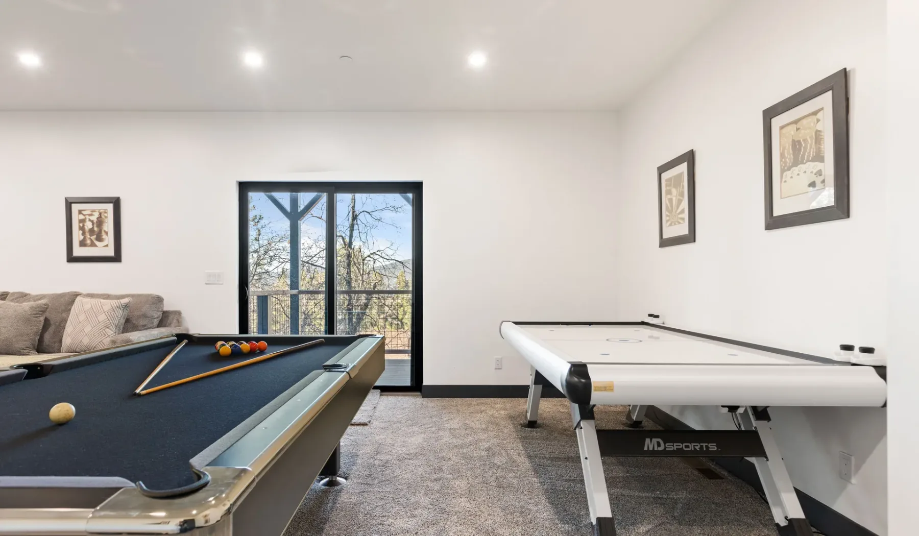 Una sala de juegos con una mesa de billar y una mesa de ping-pong.