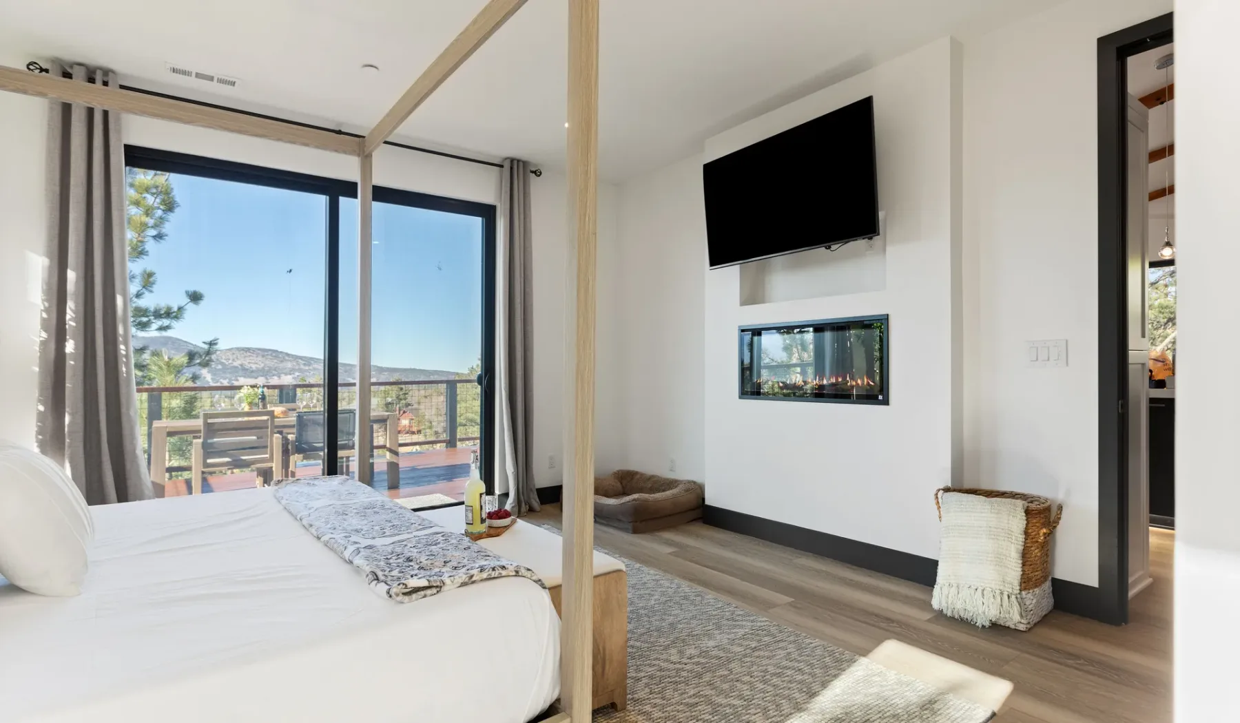 Un dormitorio luminoso da a un balcón, con una cama y un televisor en la pared.