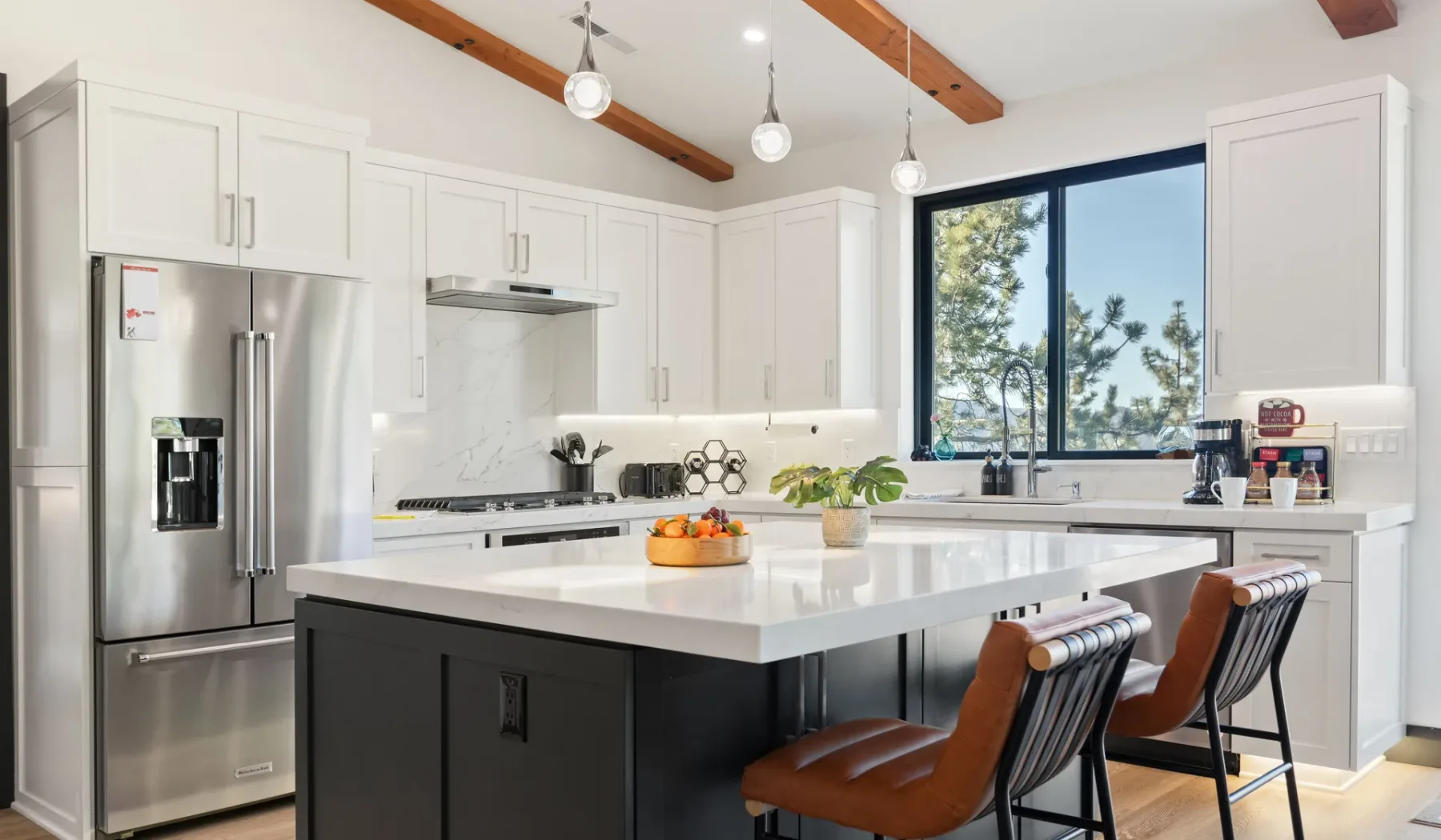 Una cocina luminosa con gabinetes blancos, una isla grande y asientos de barra.