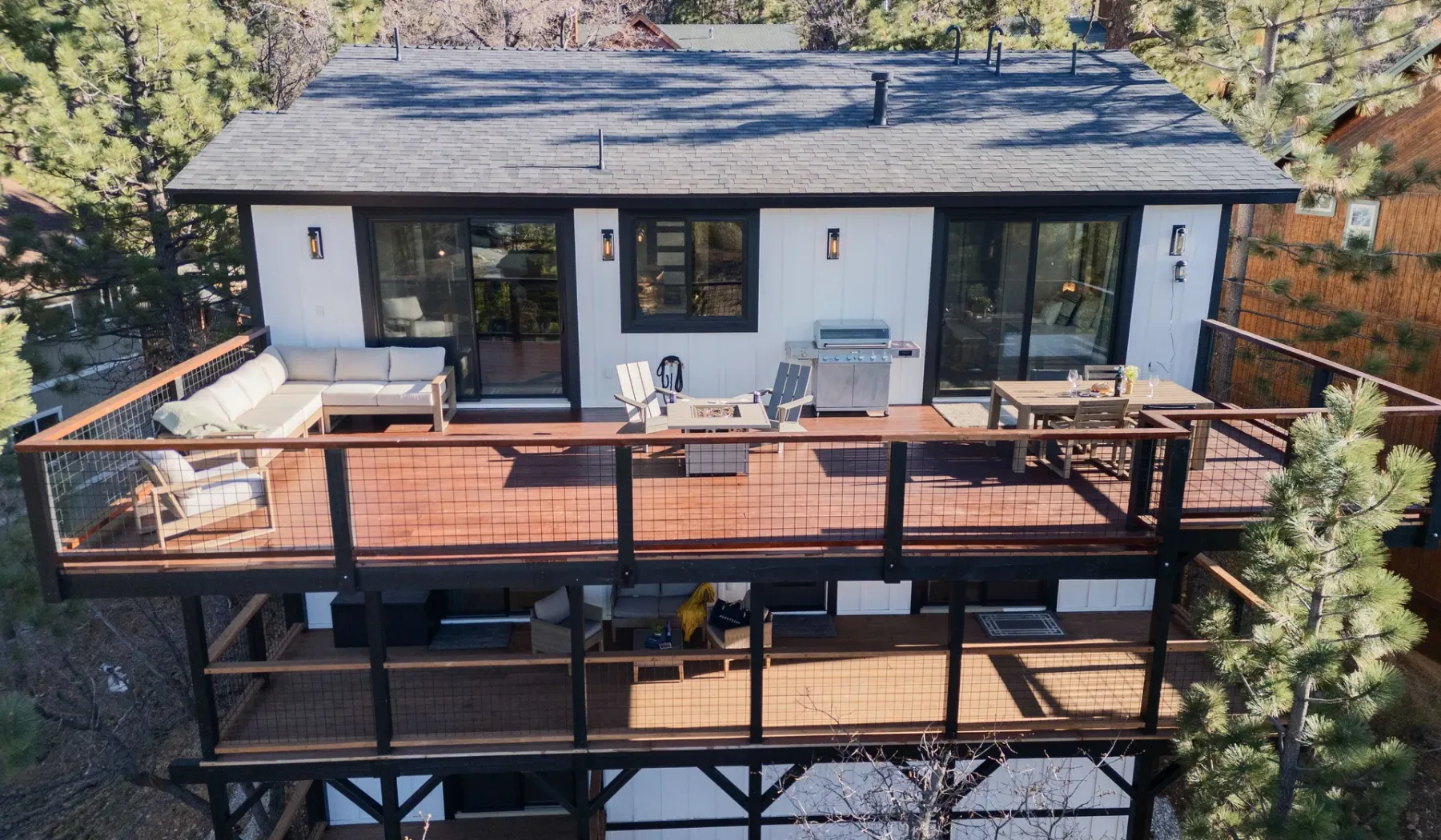 Una casa moderna con una amplia terraza de madera y asientos al aire libre.