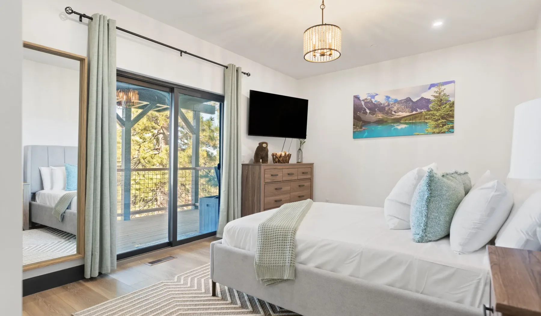 Un dormitorio luminoso con una cama bien hecha y puertas corredizas de vidrio que dan a un balcón.