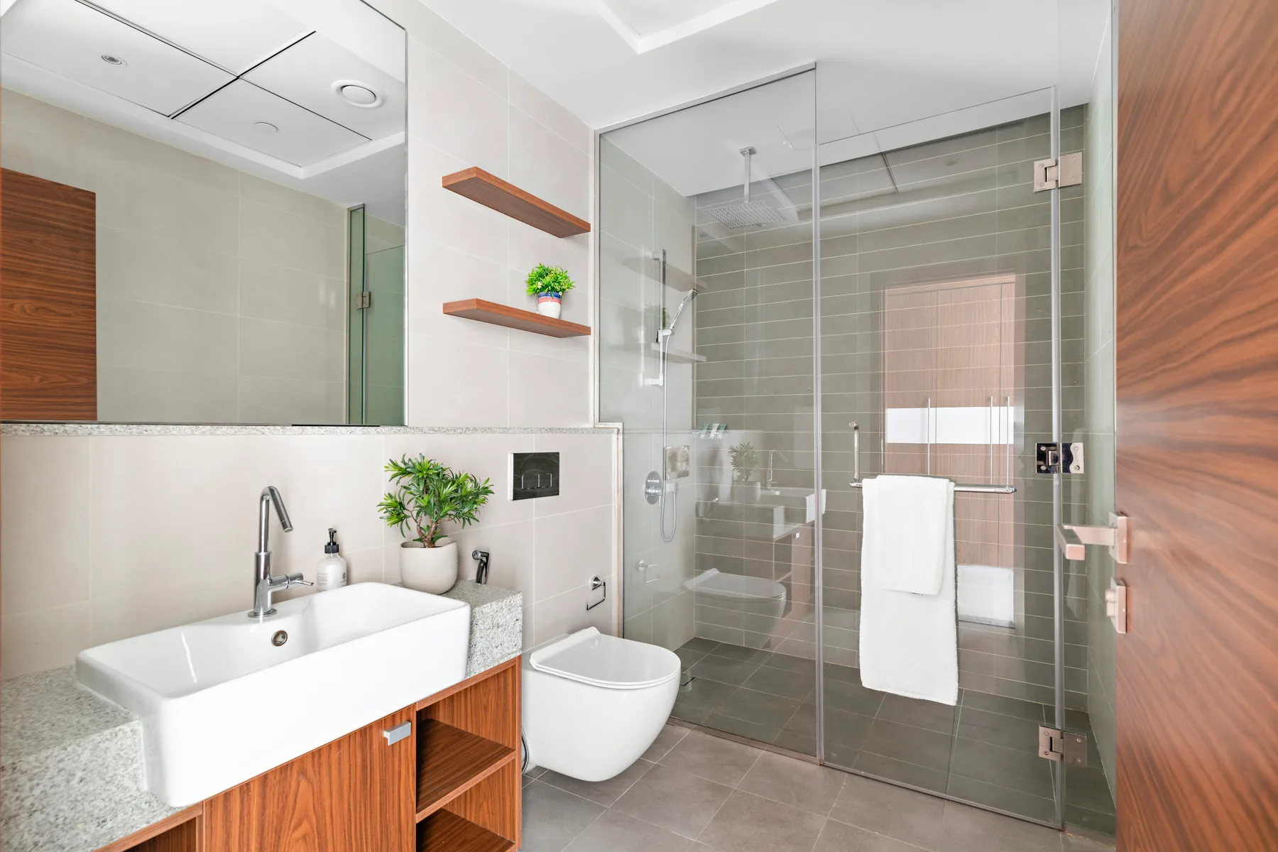 A modern bathroom with a sink, toilet, and glass shower.