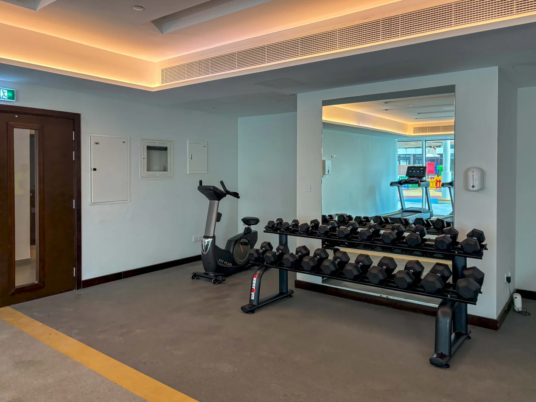 A small gym with exercise equipment and a mirrored wall.