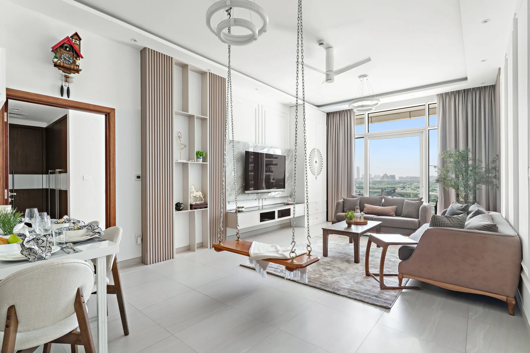 A bright living room with seating, a television, and large windows.