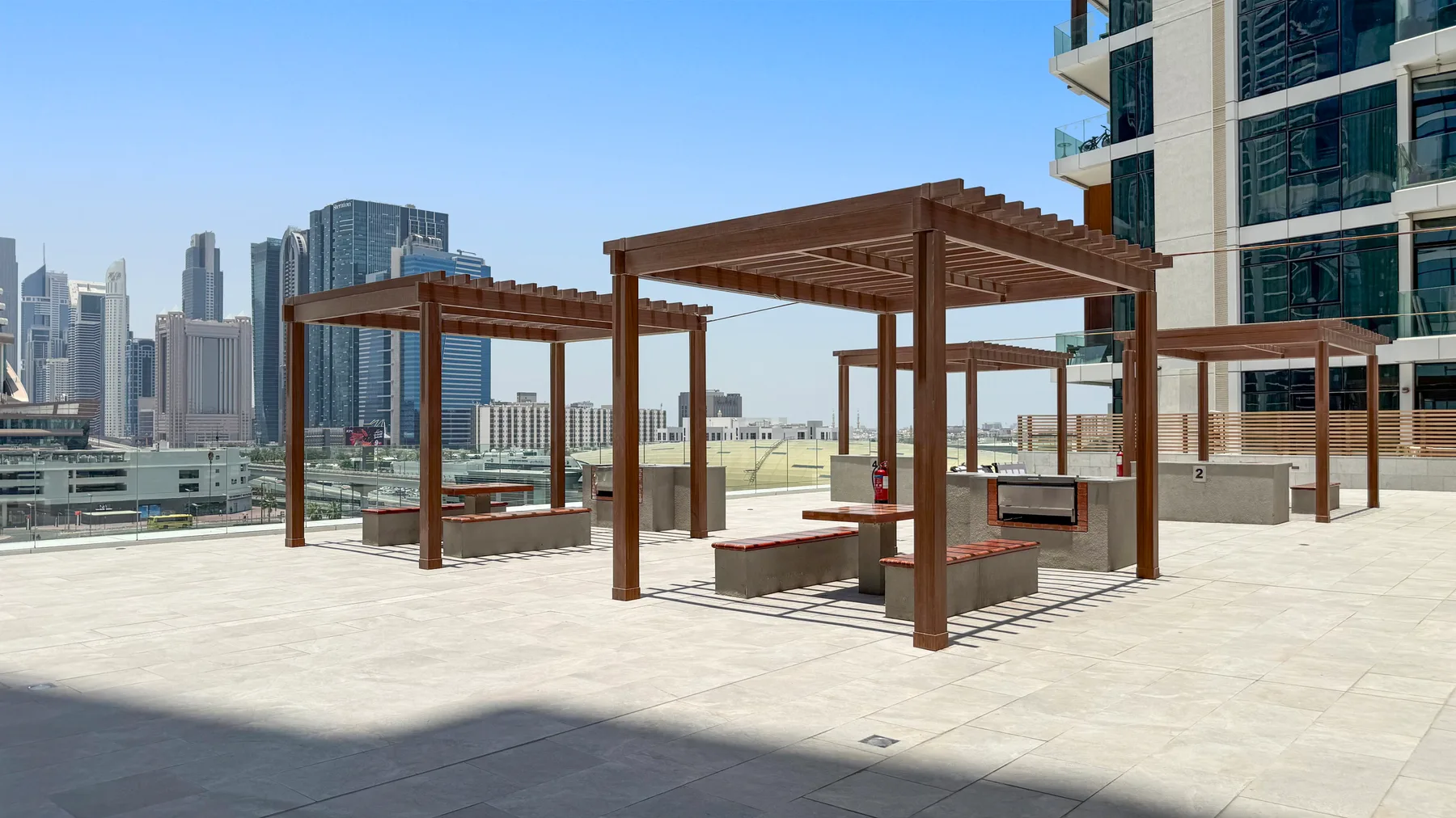 A rooftop terrace with wooden pergolas and a city skyline in the background.