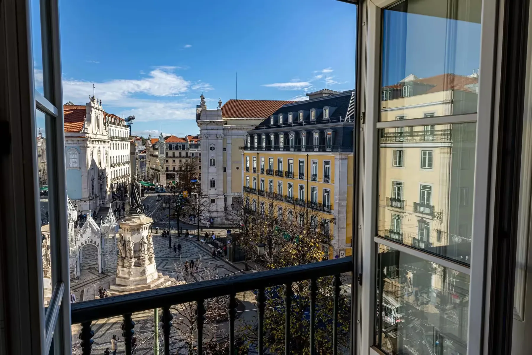Lisbon square viewed through a window and balcony railing.