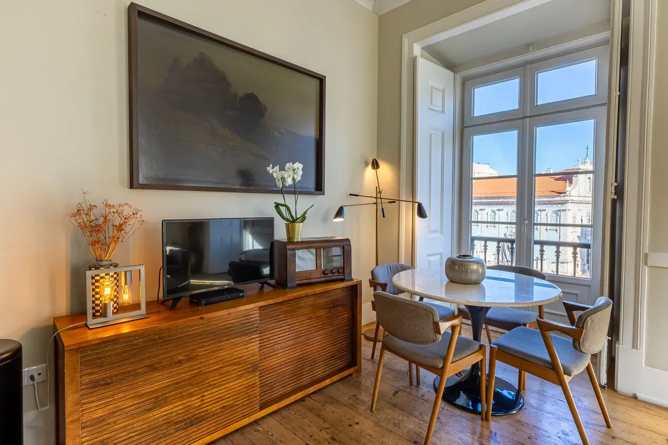 Dining area with table, chairs and balcony view.