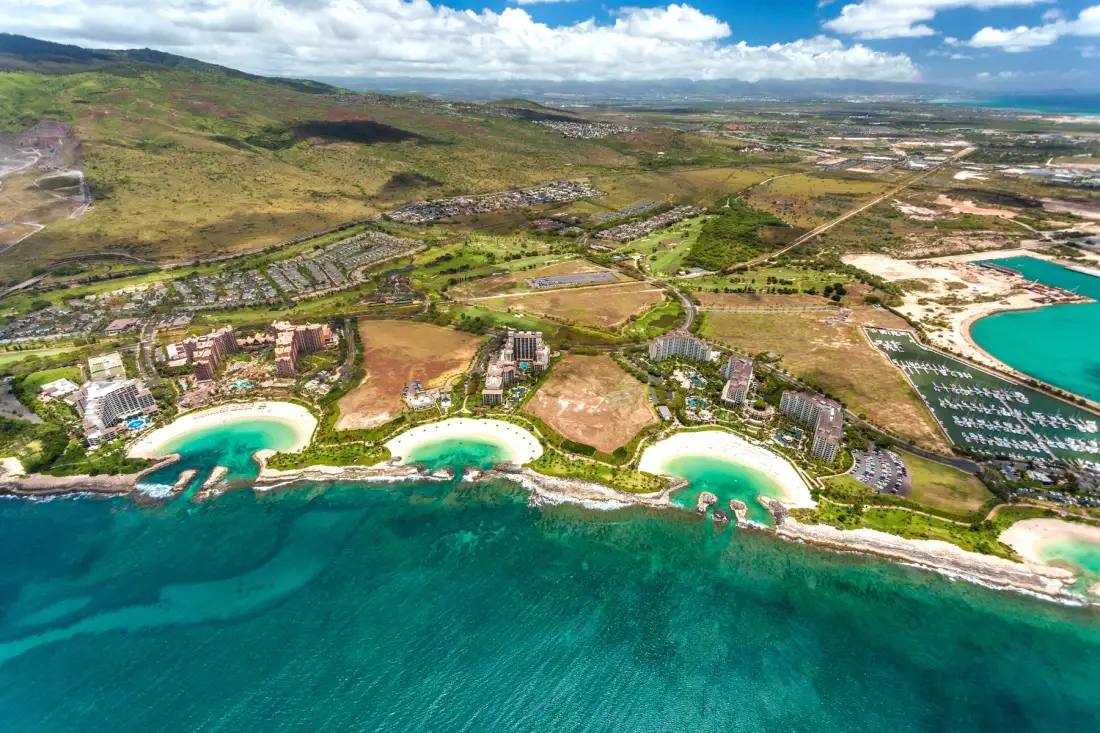 Vista aérea de una zona turística costera con agua turquesa y playas curvas.