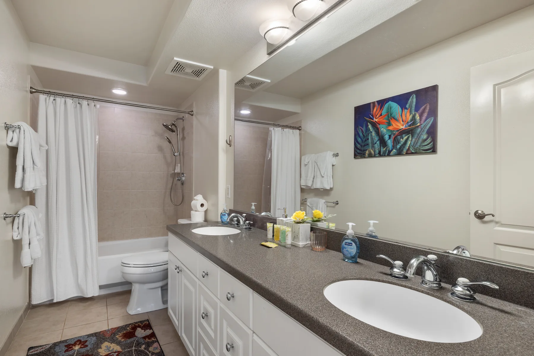 Un baño con un tocador largo, lavabo y bañera con cortina.