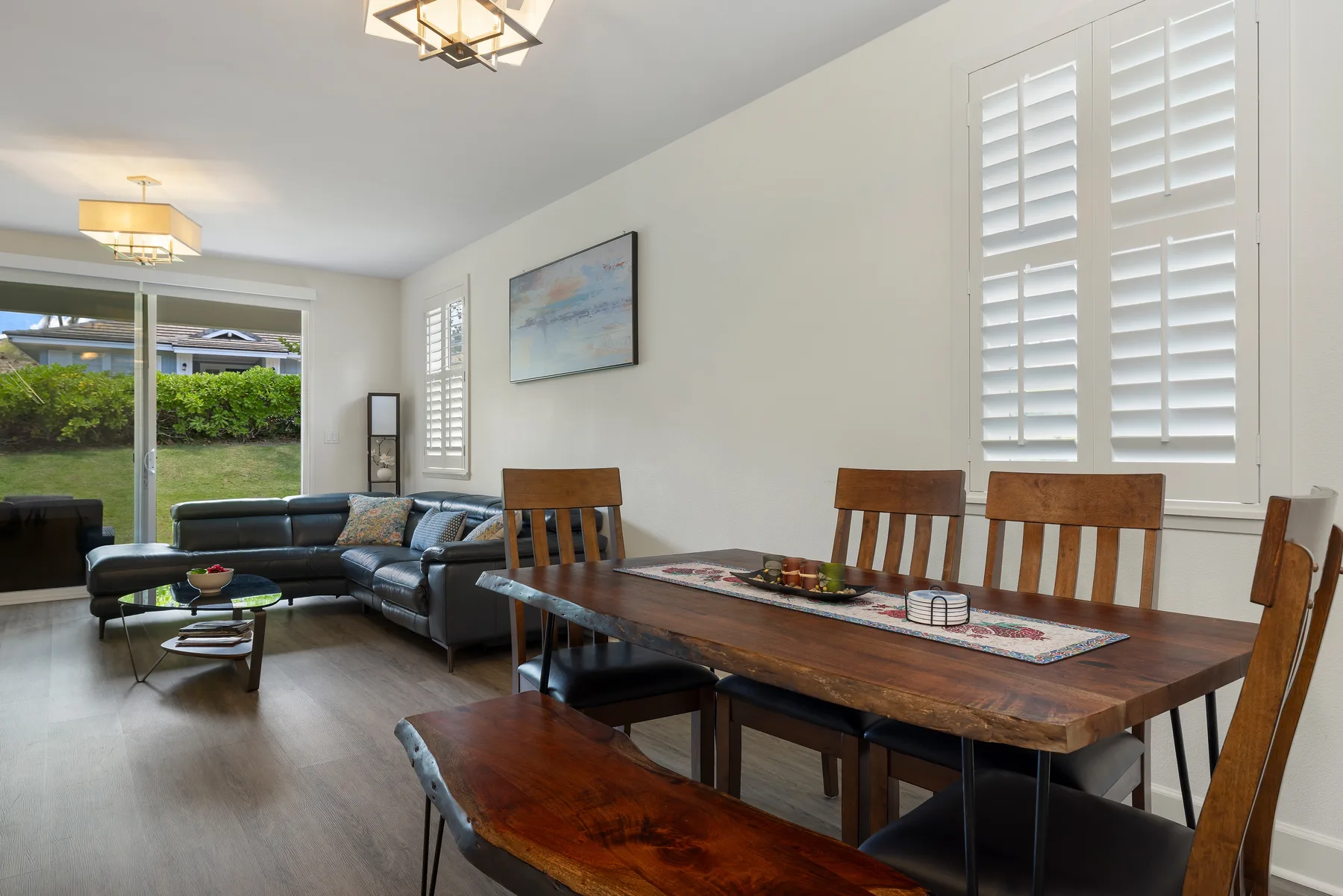 Un comedor y sala de estar con una mesa de madera y asientos junto a grandes ventanas.