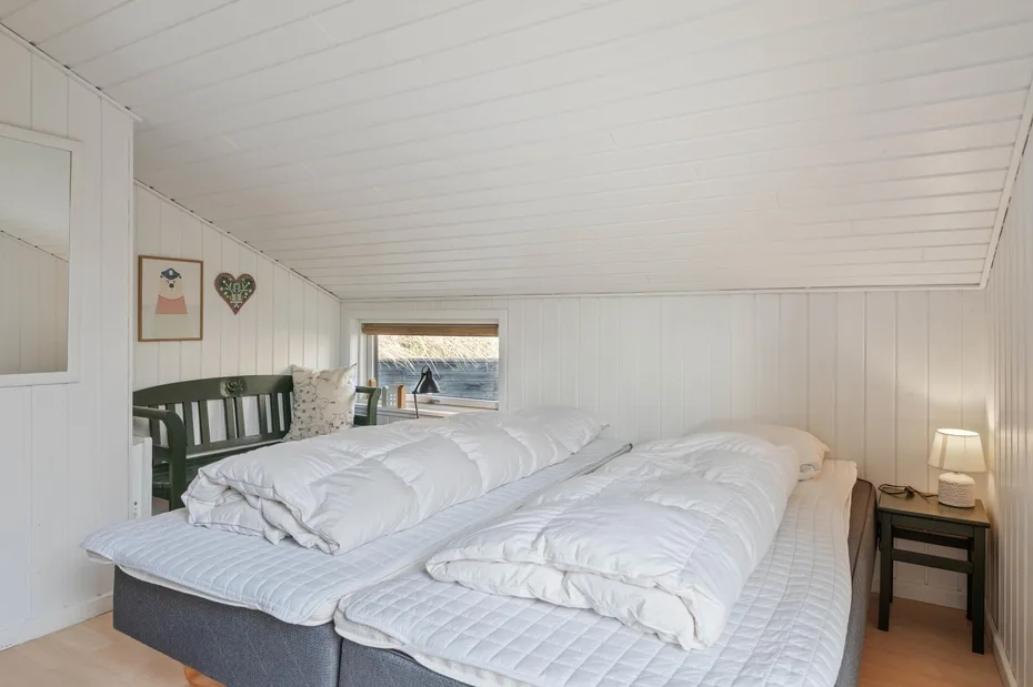 Un dormitorio con dos camas y una ventana con vistas al agua.
