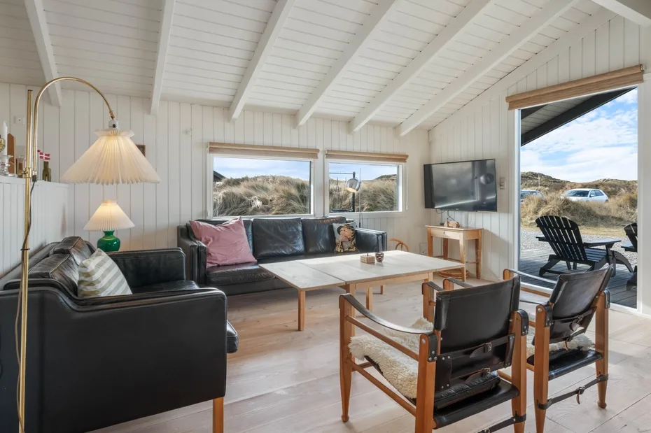 Una sala luminosa con asientos, una mesa de centro y grandes ventanas con vistas al exterior.