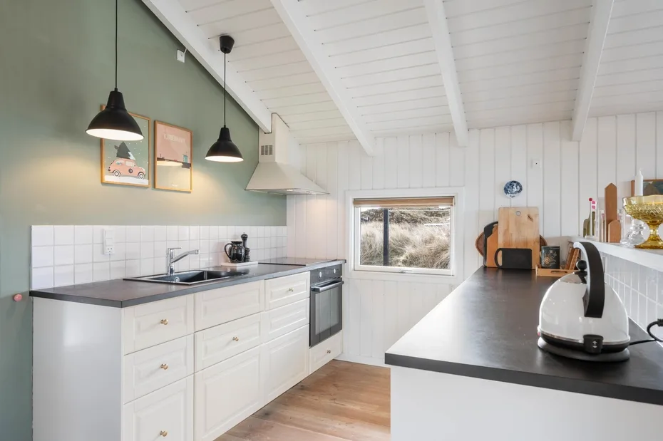 Una cocina luminosa con gabinetes blancos, encimeras oscuras y una ventana.