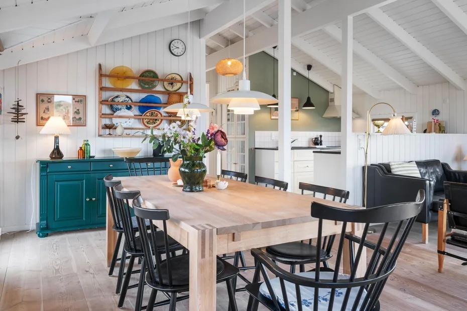 Un comedor diáfano y luminoso tiene una mesa de madera y armarios de cocina color turquesa.