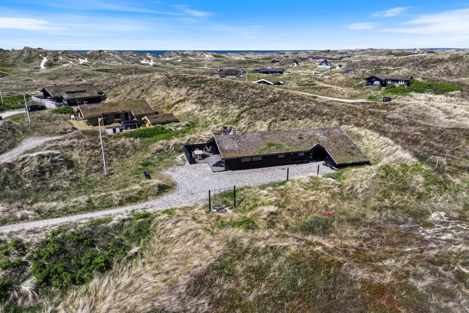 Vista aérea de edificios bajos dispersos en un paisaje de dunas cubiertas de hierba.