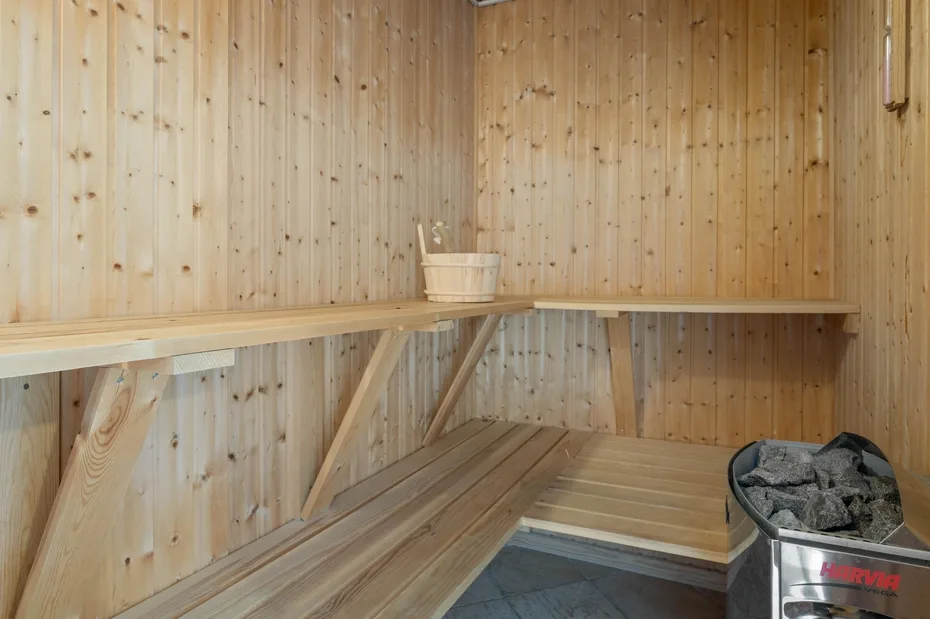 Una sauna revestida de madera con bancos escalonados y un cubo.