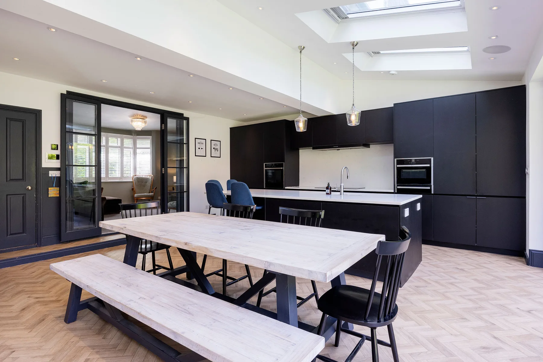 A spacious kitchen and dining area with dark cabinets and a long wooden table.