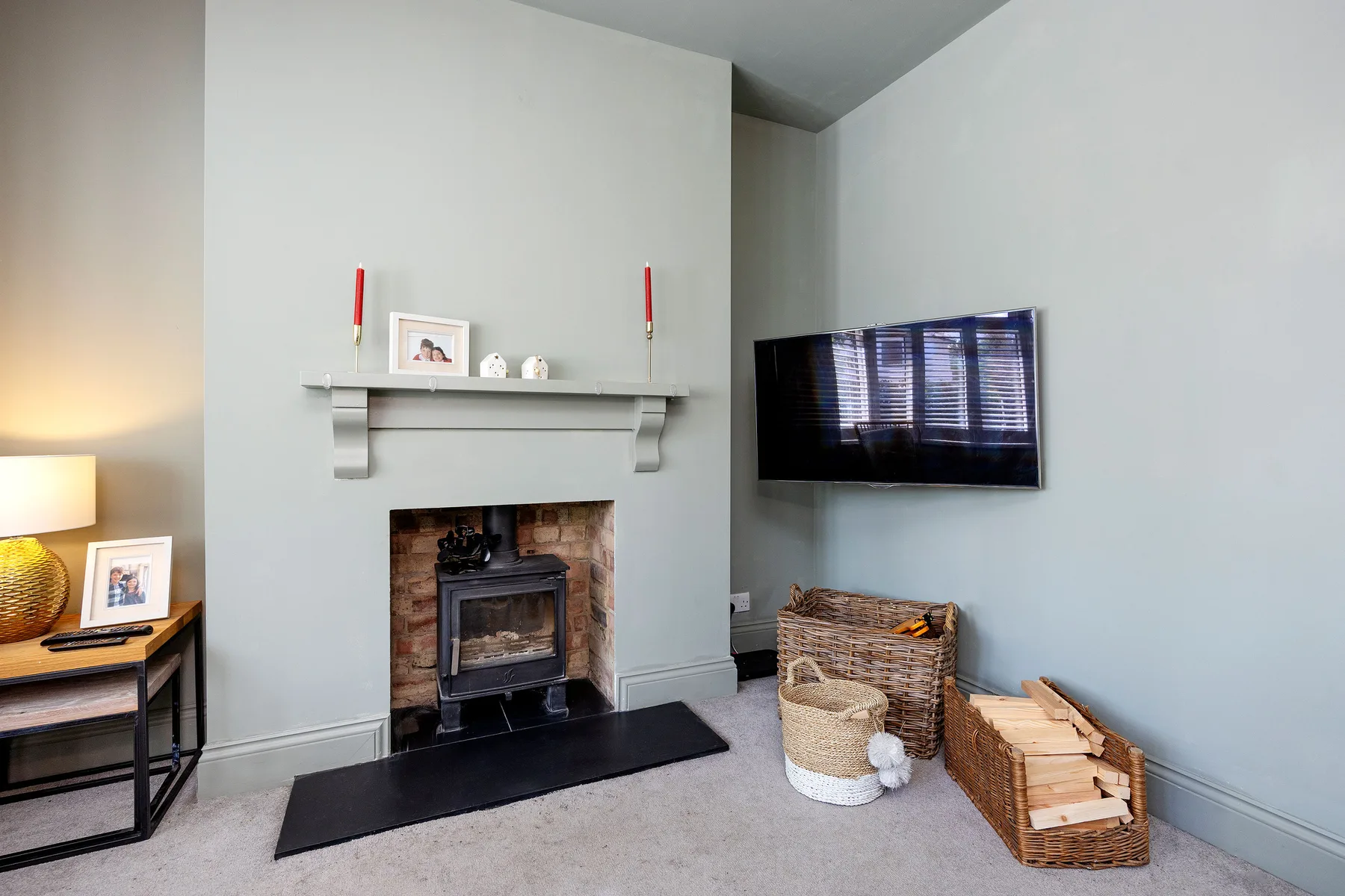 A living room with a fireplace, wall-mounted television, and woven baskets.