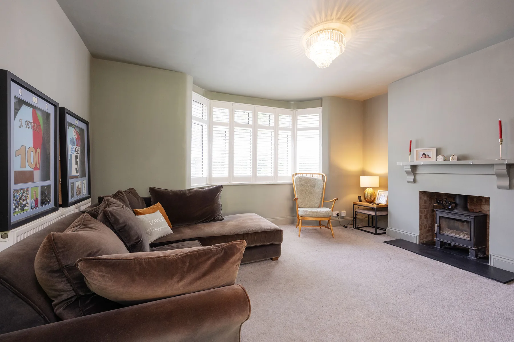 A living room with a sectional sofa, bright bay windows, and a fireplace.