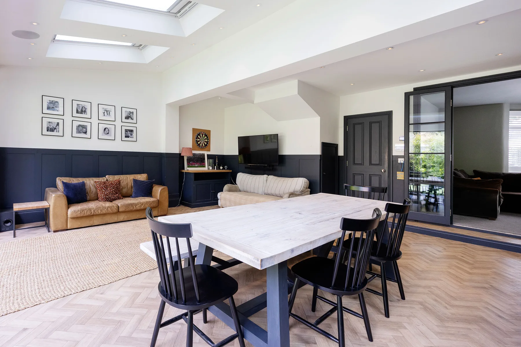 A bright open-plan living and dining area with seating around a large table.