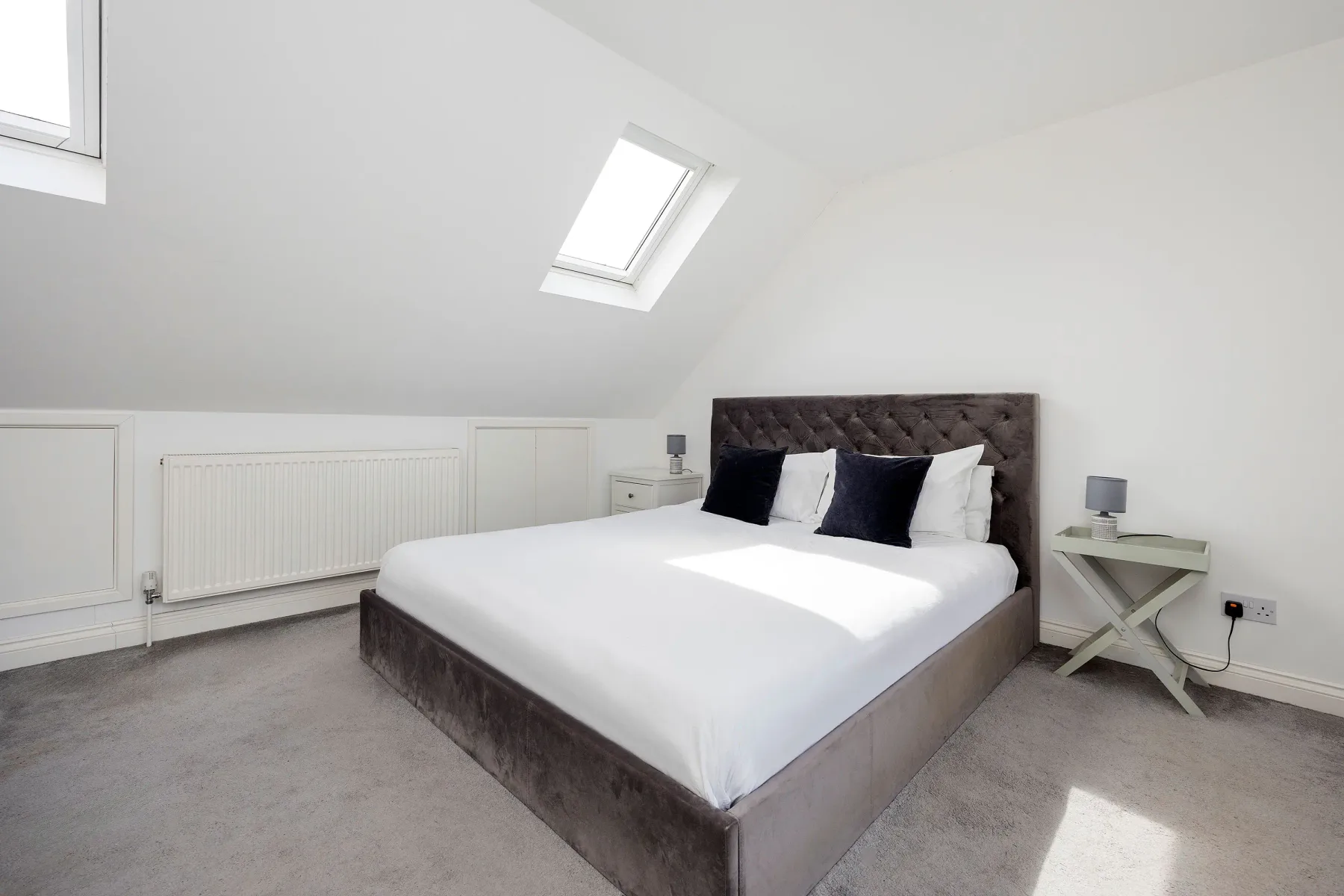 A bright attic bedroom with a large bed beneath a skylight.