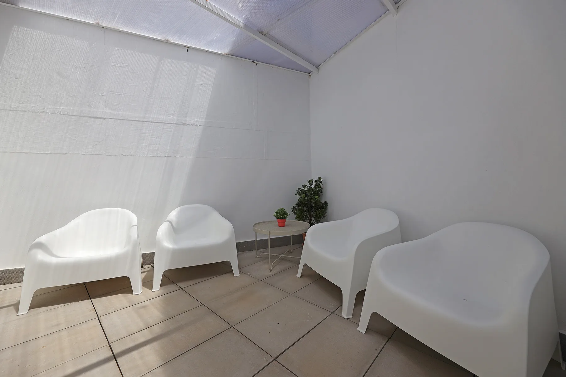 A tiled terrace with white seating and a small potted plant.