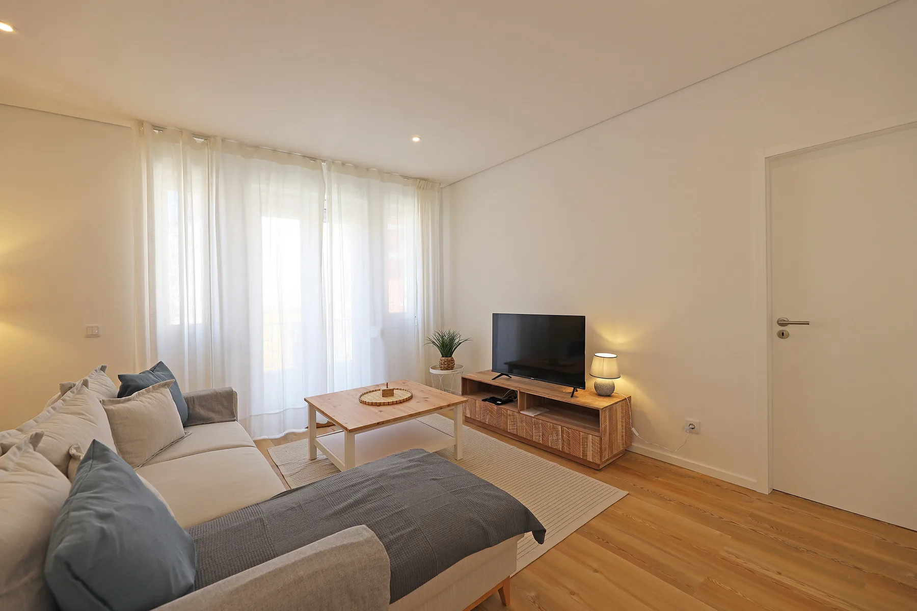 A bright living room with seating, a coffee table, and a television.