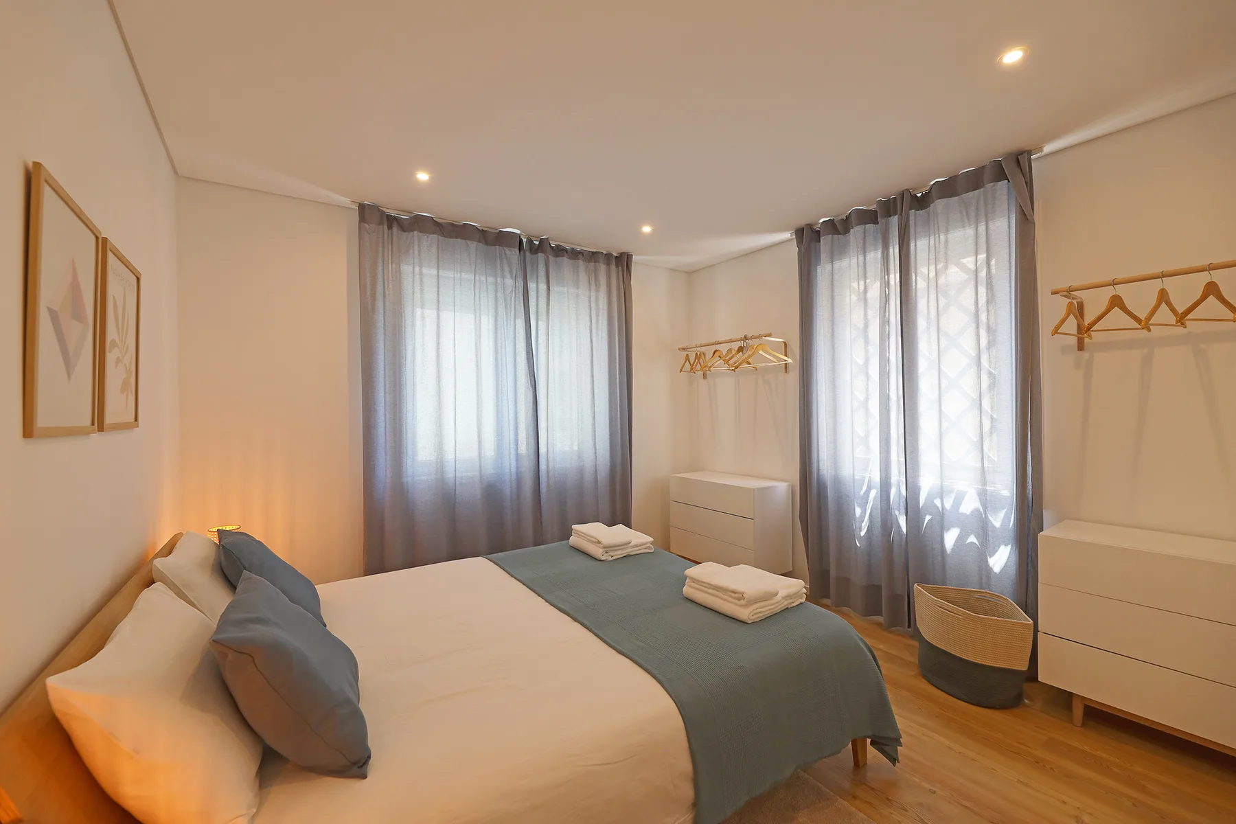 A bedroom with a bed, folded towels, and sheer curtains.
