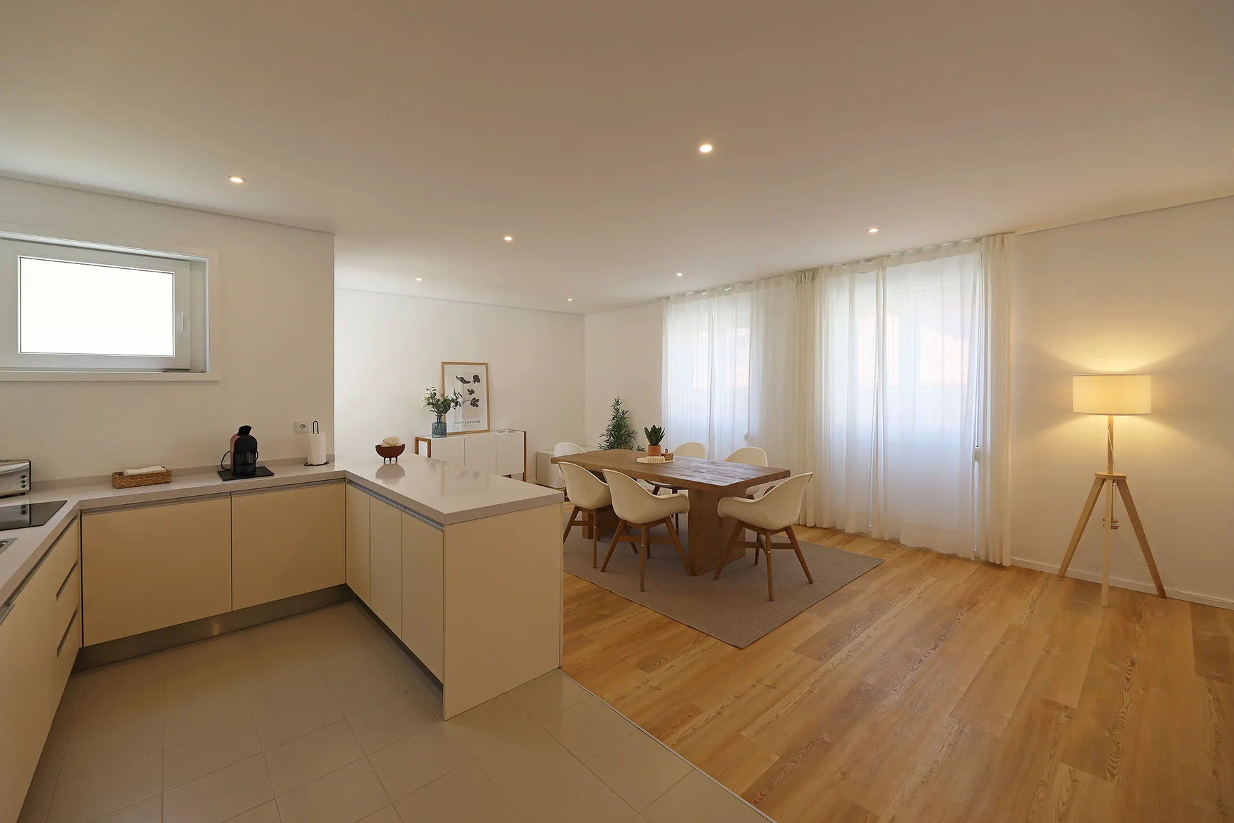 An open-plan kitchen and dining area with a table beside large windows.