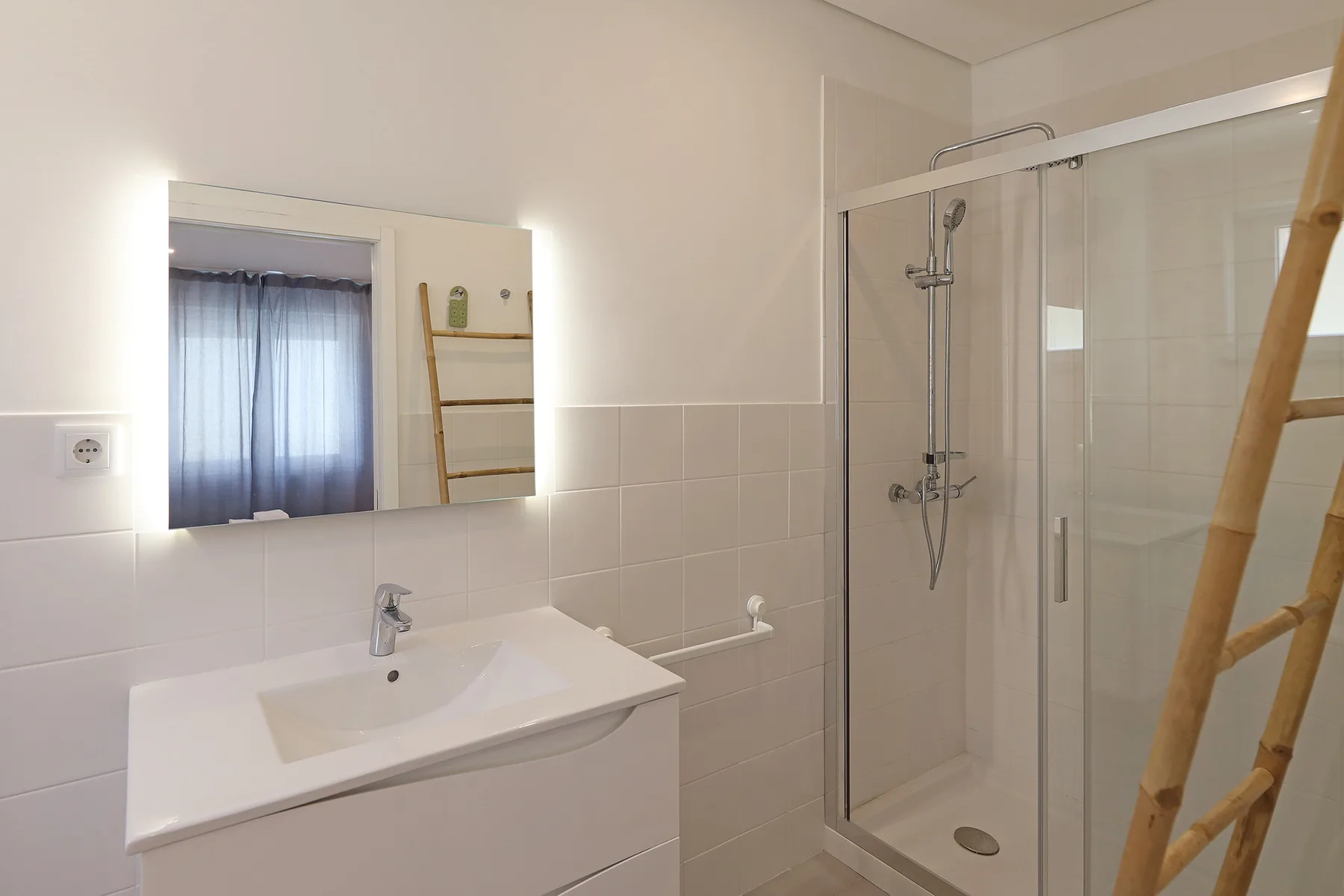 A bathroom with a sink and a glass-enclosed shower.
