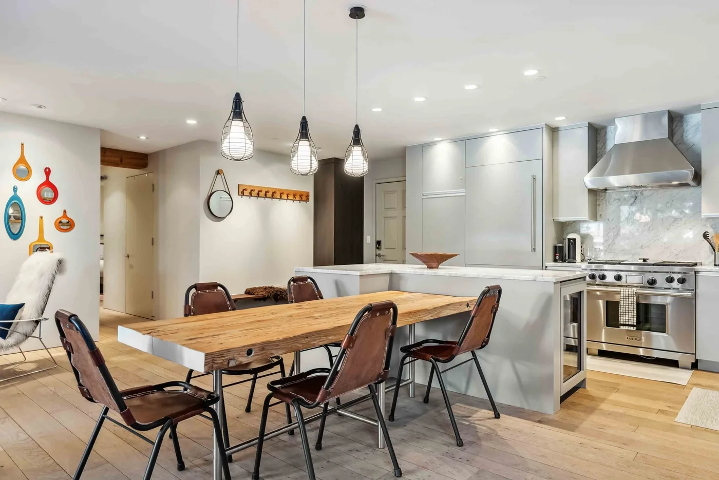 Una cocina abierta con comedor, mesa de madera y lámparas colgantes.
